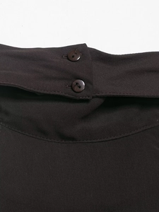 Détail des doubles boutons polis sur un haut dos nu tissé de couleur marron foncé