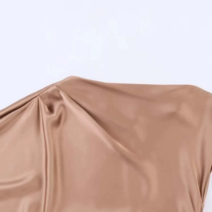 Détail de l'épaule plissée et de la texture soyeuse de la robe midi en satin couleur champagne