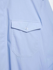 Vue détaillée d'une chemise bleu clair avec une poche à rabat et un bouton blanc