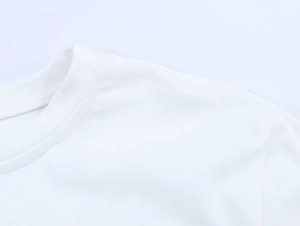 Close-up of the round neckline and reinforced shoulder seams on a white cotton T-shirt