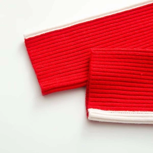 Dettaglio ravvicinato della maglia a coste rossa con bordo bianco a contrasto della tuta