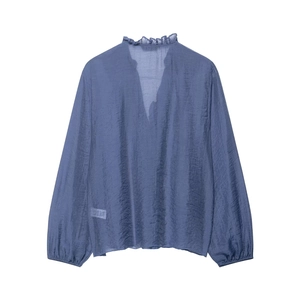 Detail of dusty blue chiffon shirt featuring ruffled collar and V-neckline texture