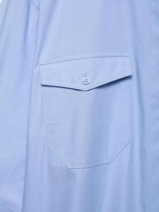 Détail de la poche de poitrine de chemise bleu clair avec rabat, bouton et couture