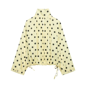 Detailed view of the yellow polka dot jacket showing stand collar and drawstring hem