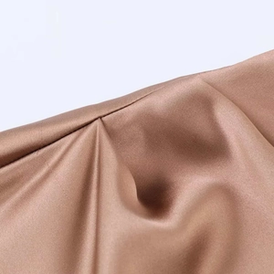 Vue détaillée du tissu en satin bronze et des coutures de qualité sur la robe midi