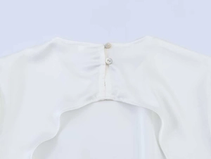 Detail of white chiffon top featuring double button closure and back cutout design