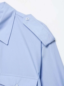 Détail de chemise en coton bleu clair avec épaulette boutonnée et couture de poche poitrine