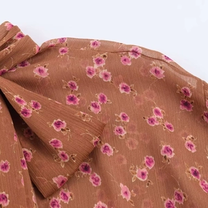 Detail of floral chiffon fabric with rose pattern and a tied bow decoration