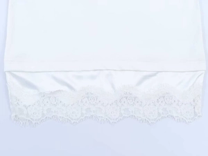 Detail of white long sleeve top featuring layered hem with satin fabric and eyelash lace trim