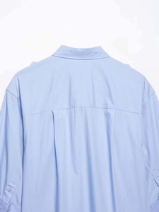 Détail du dos d'une chemise bleu clair avec pli creux et bouton de manchette