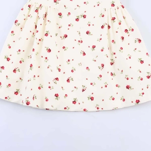 Détail de l'imprimé floral rose rouge et de la taille froncée sur la robe crème