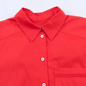 Detailed close-up of red shirt collar with contrasting white buttons and pocket stitching