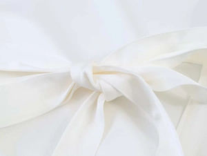 Macro view of a white chiffon blouse showing the detailed tie-knot and fine fabric texture