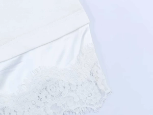 Detail of white top hem featuring exquisite floral lace stitching and eyelash fringe finish