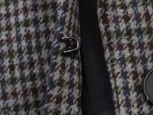 Macro detail of houndstooth wool fabric showing texture and metal hook closure