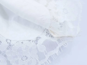 Close-up of intricate white floral lace detailing and soft inner lining on long sleeve top