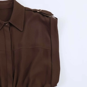 Detail of brown shirt dress with classic collar, shoulder straps and metallic hardware