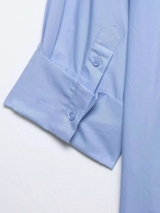 Détail du poignet d'une chemise bleu clair avec coutures et boutons translucides