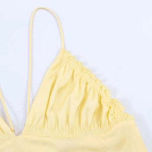 Close-up of light yellow midi dress with thin straps, ruched chest, and ruffled edges