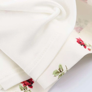 Gros plan détaillé du tissu floral avec roses rouges et coutures fines sur l'ourlet