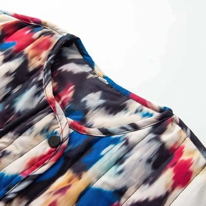 Détail du col rond avec bouton noir sur veste en coton à imprimé abstrait de style tie-dye