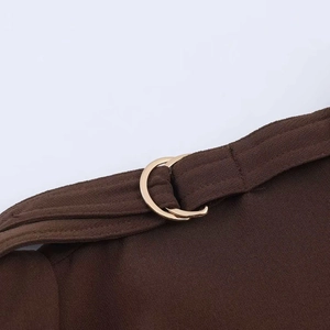 Detailed close-up of brown fabric texture with a decorative gold double-ring buckle detail