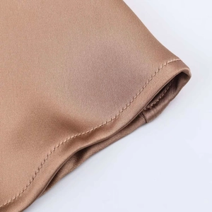 Gros plan détaillé sur la texture du tissu satiné et les coutures précises sur l'ourlet