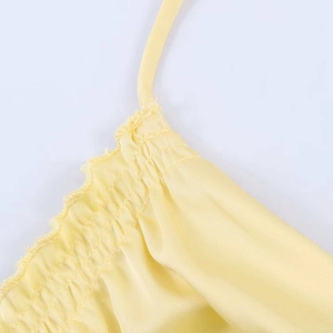 Close-up of yellow satin dress featuring delicate spaghetti straps and ruched neckline detail