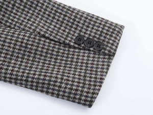 Close-up of three matte black buttons on a plaid tweed blazer sleeve with fabric detail