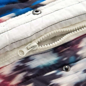 Détail de la doudoune matelassée tie-dye avec fermeture éclair et bouton-pression en métal