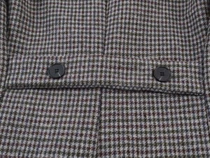 Detail of classic houndstooth blazer showing back waist strap and black buttons