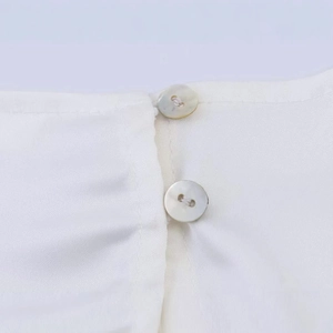 Detail of white chiffon blouse with pearlescent buttons and silky fabric texture