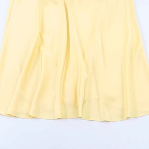Detail of light yellow satin dress showing silky fabric texture and draped pleats