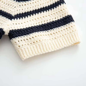 Detail of the crochet hollow knit texture and ribbed cuff on a striped V-neck top