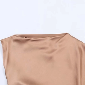 Gros plan détaillé sur la texture satinée champagne et le drapé élégant du col