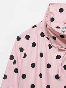 Detail of pink polka dot long sleeve blouse with stand collar and woven fabric texture