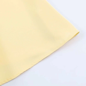 Detailed view of the smooth pale yellow satin fabric and neat stitching on dress hem