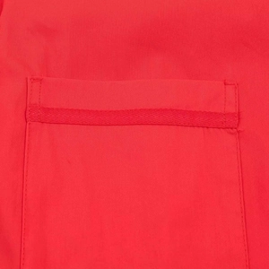 Close-up of pocket stitching and textured trim on the red loose-fit shirt fabric