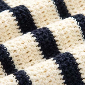 Close-up of black and white striped knit fabric showing thick crochet texture and soft yarn