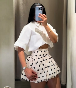 Nahaufnahme von weißem Crop-Shirt und hoch tailliertem gepunktetem Ballonrock