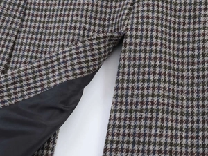 Detail of vintage houndstooth fabric in brown and green with smooth black inner lining