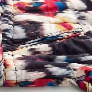Vue détaillée d'une veste matelassée tie-dye colorée mettant l'accent sur la couture