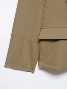 Detail of khaki utility jacket showing twill fabric texture and metal snap button pocket