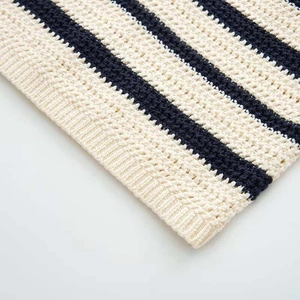 Detail of navy blue and cream striped knit top with textured crochet finish and ribbed hem