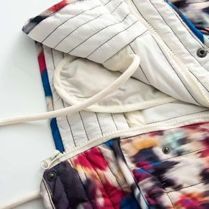 Détail de la doudoune tie-dye colorée avec doublure matelassée rayée et zip blanc