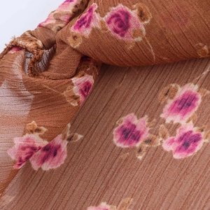 Close-up of pleated chiffon floral fabric with delicate brown and pink flower patterns