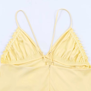 Close-up of light yellow satin dress featuring delicate ruffled V-neck and thin straps