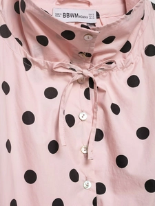 Close-up of pink polka dot jacket featuring a stand collar and elegant pearl buttons