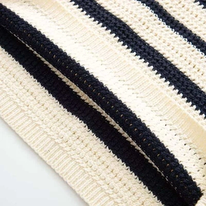 Detail of loose knit fabric with thick texture and black stripes on cream background