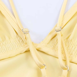Detail view of adjustable spaghetti straps and smocked back on yellow satin dress